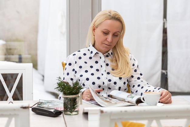 Schöne, reife Frau, Geschäftsfrau mit blonden Haaren, lose Arbeiten, die in einem Kaffee sitzen