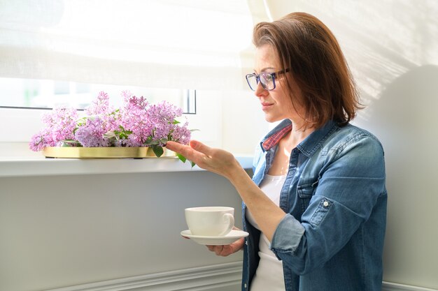 Schöne reife Frau zu Hause mit Blumen