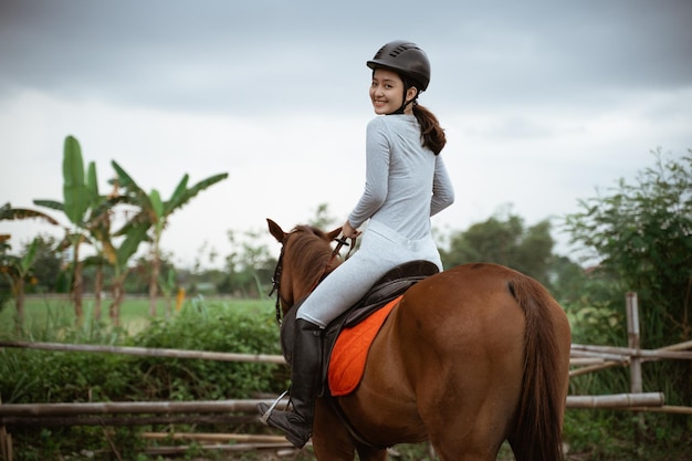 Schöne Reitersportlerin, die Reiten auf dem Hintergrund im Freien praktiziert