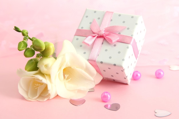 Schöne romantische Geschenkbox und Blume auf rosa Hintergrund