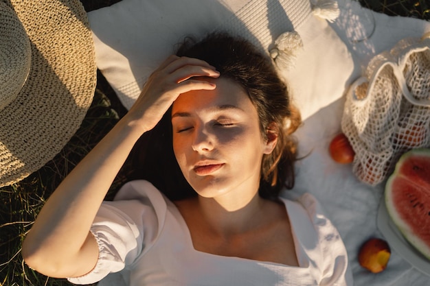 Schöne romantische junge Frau, die auf einer Decke auf einer Sommerwiese liegt Zeit für sich selbst Entspannen auf der Sommerwiese Ein Mädchen mit schönem Haar genießt das Sommerwetter