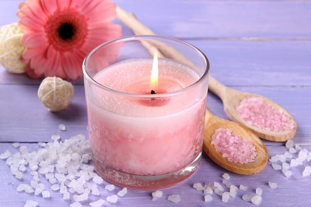 Schöne rosa Kerze mit Blume auf purpurrotem hölzernem Hintergrund