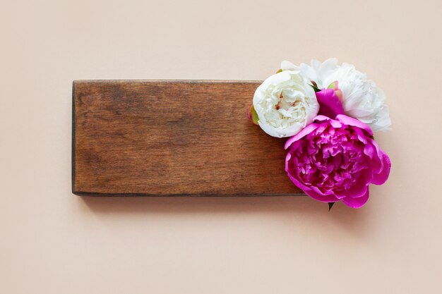 Schöne rosa und weiße Pfingstrosen auf einem hölzernen Hintergrund