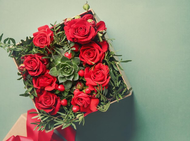 Schöne Rosen in Geschenkbox auf farbigem Hintergrund