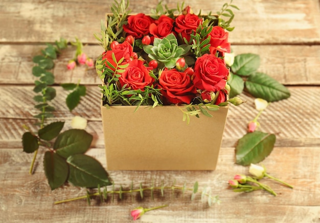 Schöne Rosen in Geschenkbox auf Holzhintergrund