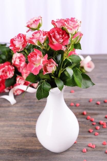 Schöne Rosen in Vase auf dem Tisch auf hellem Hintergrund