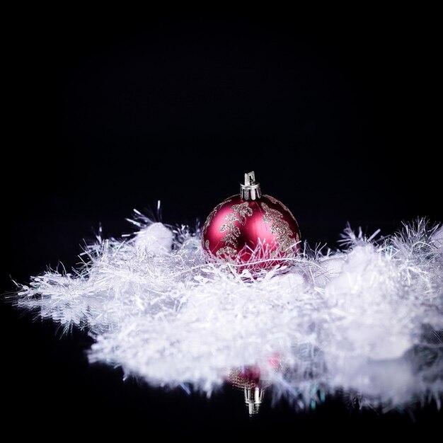 Schöne rote Weihnachtskugel auf schwarzem Hintergrund