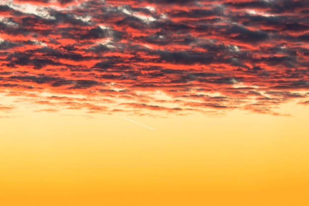 Schöne rote Wolken, die bei Sonnenuntergang von den Sonnenstrahlen beleuchtet werden, schweben über den gelb-goldenen Himmel.