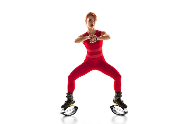 Schöne rothaarige Frau in einer roten Sportkleidung, die in ein Känguru springt