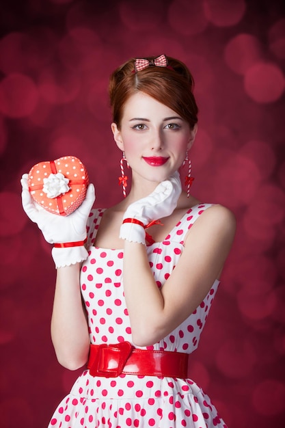 Schöne Rothaarigefrauen mit Geschenk. Foto im Retro-Stil mit Bokeh im Hintergrund.