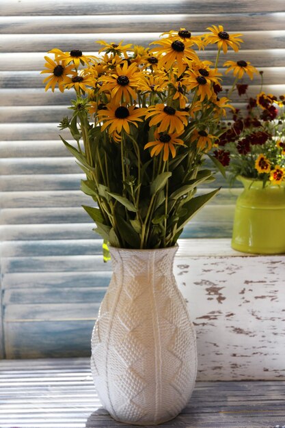 Schöne Rudbeckia-Blumen in Vase auf Holztisch zu Hause