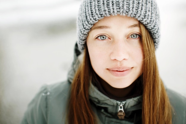 Schöne ruhige lächelnde junge Frau im warmen Outfit des Winters, das draußen im verschneiten Parkporträt aufwirft