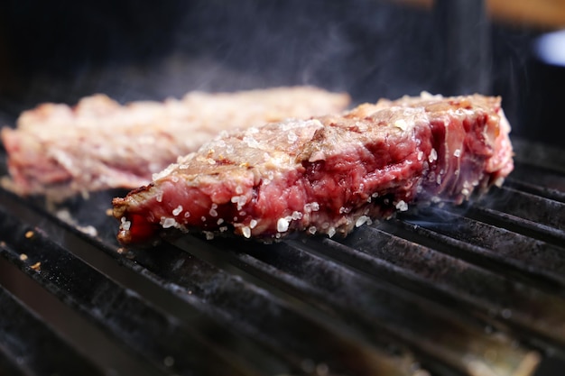 Schöne saftige Picanha Nahaufnahme mit Grillspuren auf dem Grill mit glühender Kohle im Hintergrund