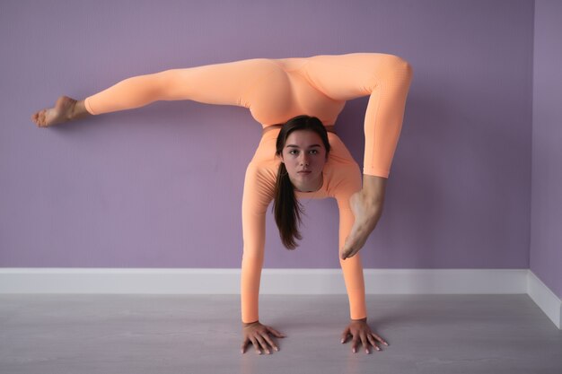 Schöne schlanke Frau in Sportoveralls beim Yoga stehend in einer Pose von ausgleichenden Asanas