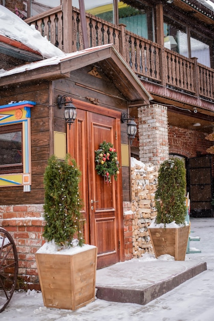 Schöne schneebedeckte Veranda mit Weihnachtskranz in einem Holzhaus im Winter