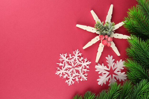 Schöne Schneeflocken mit Tannenzweig auf rosa Hintergrund