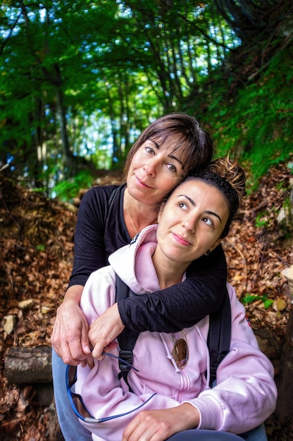 Schöne, schöne, reife Dame, Mutter, Frau, die ihre brünette Tochter im Wald umarmt.