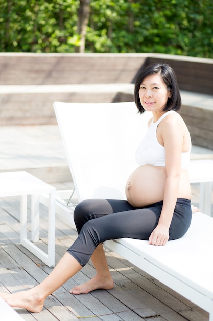 Schöne schwangere asiatische Frau des Porträts entspannen sich im Park