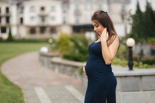 Schöne schwangere Dame im blauen Kleid lächeln und haben Spaß.