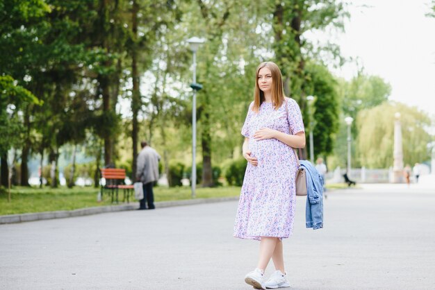 Schöne schwangere Frau, die im Park entspannt