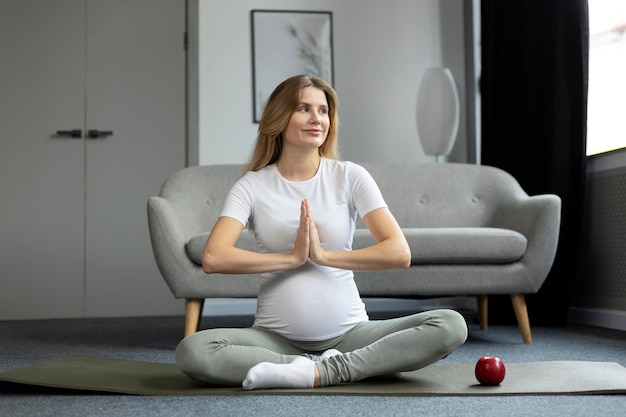 Schöne schwangere Frau, die trainiert, meditiert, Yoga macht und in Lotus-Pose sitzt. Schwangerschaftsyoga