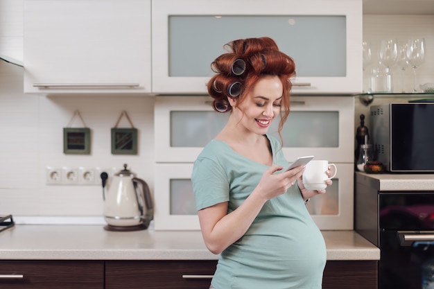 Schöne schwangere Frau mit einem Smartphone