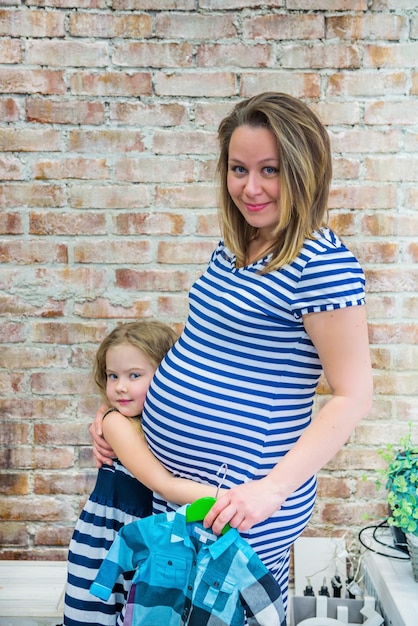 Foto schöne schwangere frau mit tochter in der nähe der wand