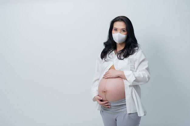 schöne schwangere Frauen, die eine Maske tragen