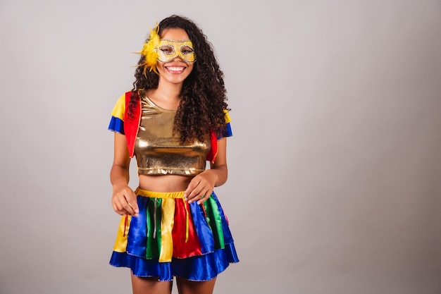 Schöne schwarze Brasilianerin mit Frevo-Kleidungskarneval, die eine Maske trägt, die Samba tanzt