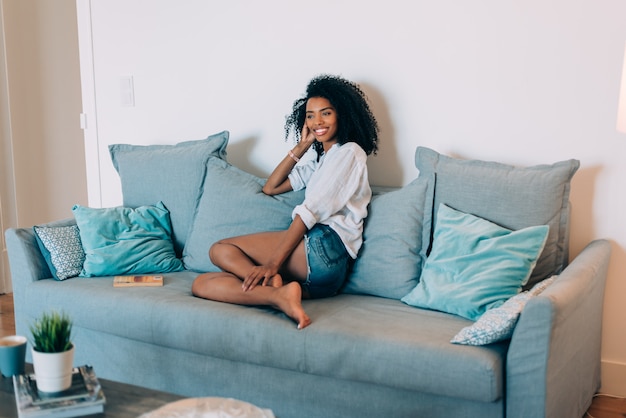 Foto schöne schwarze sitzplätze der jungen frau im sofa