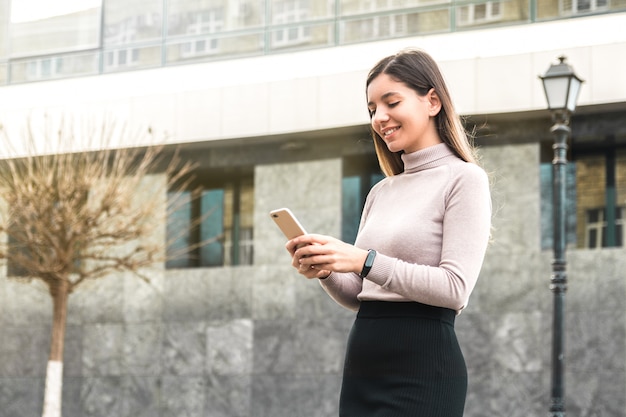 Schöne selbstbewusste Geschäftsfrau, die am Telefon vor Geschäftszentrum plaudert