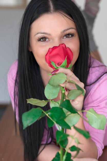 Schöne sexy junge Frau, die einzelne Rose hält