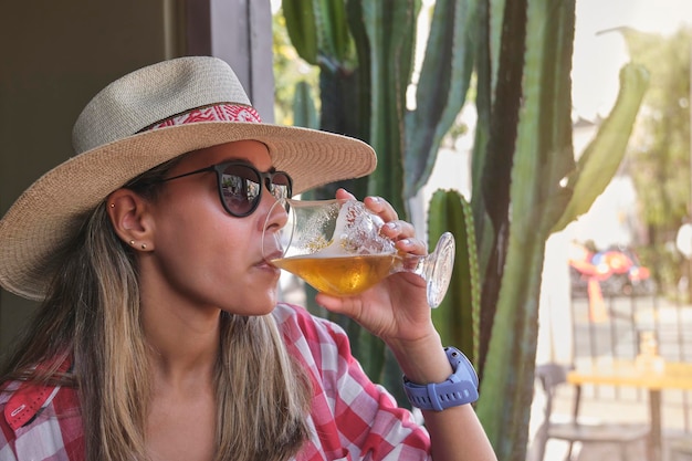 Foto schöne, sexy, modische frau, eine frau, die bier trinkt und einen sommertag in einer mexikanischen bar genießt.