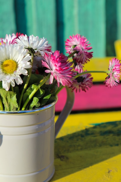 schöne Sommerblumen in einer eisernen Gießkanne auf Holzuntergrund