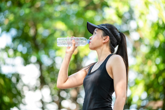 Schöne Sport Asiatin mittleren Alters trinkt Wasser nach dem Joggen, Gesundheit und Sportkonzept.