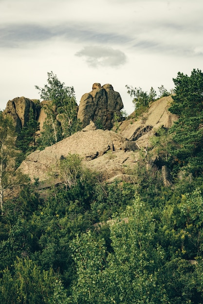 Schöne Steine in Form von zwei Personen auf dem Berg, umgeben von viel Grün. Regenwolke in Form eines Heiligenscheines über Steinköpfen.