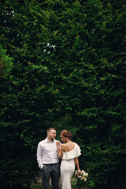 Schöne stilvolle Braut und Bräutigam auf dem begehbaren Park an ihrem Hochzeitstag