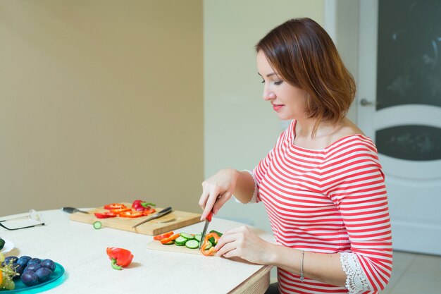 schöne stilvolle Frau, die Salat in der Küche schneidet