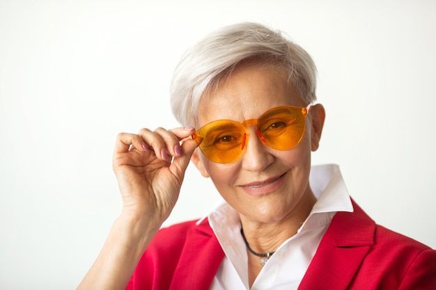 schöne stilvolle Frau im Alter in einer roten Jacke in Sonnenbrille gealtert
