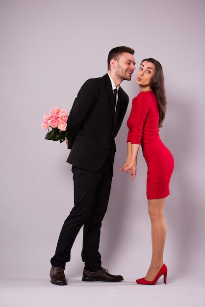 Schöne stilvolle und elegante Paare in Anzug und Kleid umarmen sich, haben Spaß und posieren isoliert im Studio. Feiertage und Veranstaltungen. Valentinstag. Tag der Liebenden