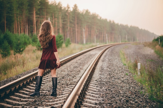 Schöne Tänzerin mit dem gelockten natürlichen Haar genießen Natur im Wald auf Eisenbahn.