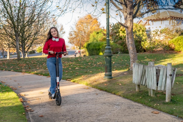 Schöne Teenagerin, die einen Elektroroller in einem Park fährt