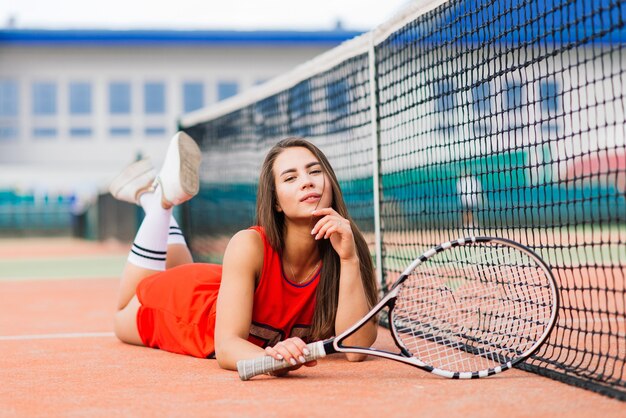 Schöne Tennisspielerin auf Tennisplatz im roten Kleid.