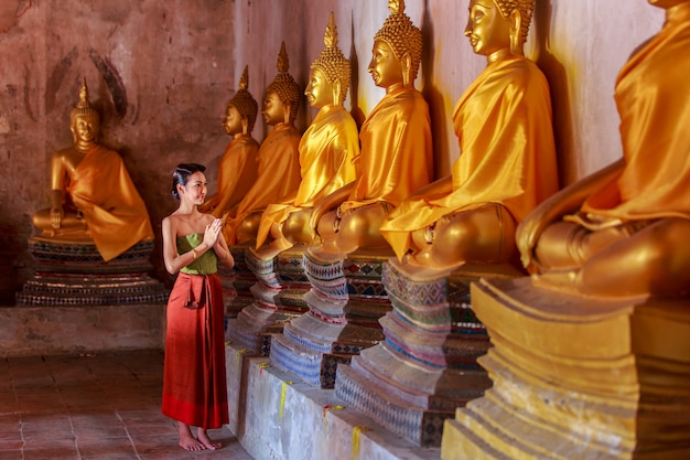 Schöne thailändische Mädchen im thailändischen traditionellen Kostüm Buddha-Statue in Ayutthaya betend