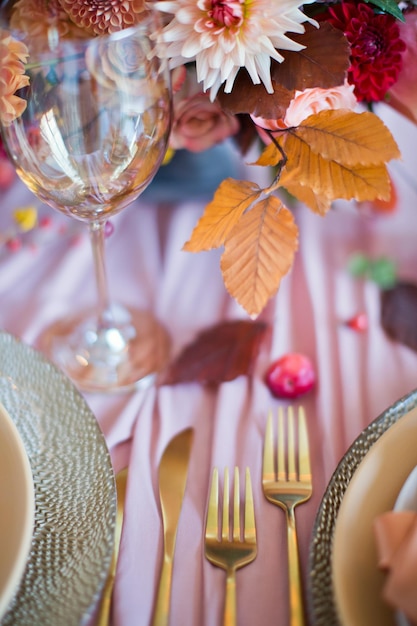 Schöne Tischdekoration mit Herbstblumen, orangefarbenen und rosa Servietten und brennenden Kerzen Herbsthochzeitskonzept