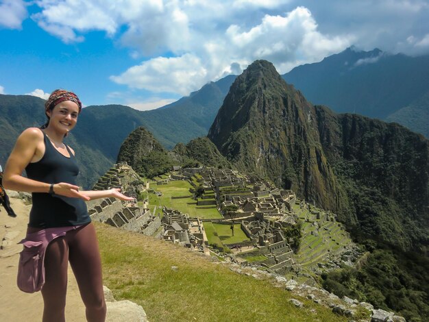 Foto schöne touristenfrau, die im heiligtum von machu picchu, urubamba - cusco - peru aufwirft.