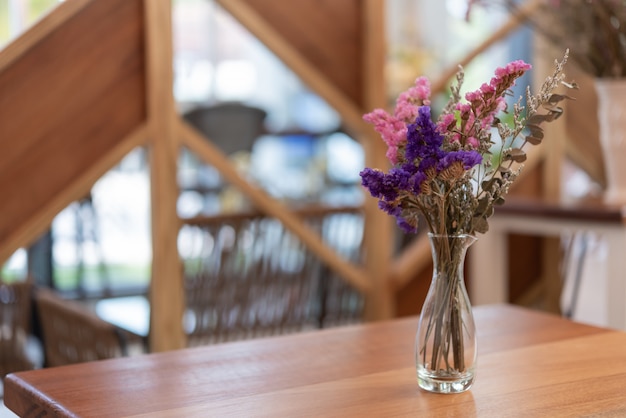 Schöne Trockenblumen im Glasvase auf hölzerner Tabelle, Restaurantinnenraum