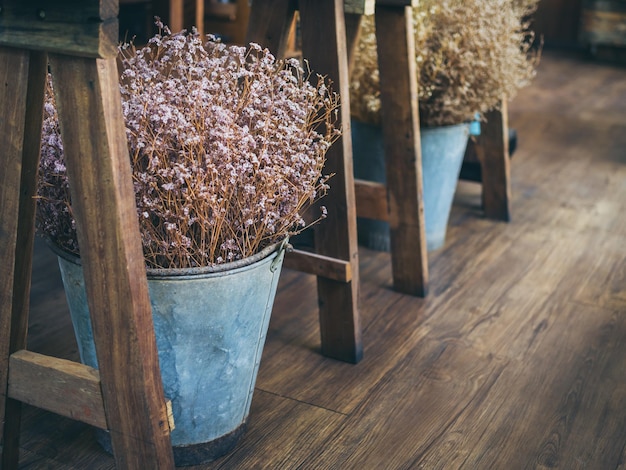 Schöne Trockenblumen im Metalleimer unter dem Holztisch auf Holzboden