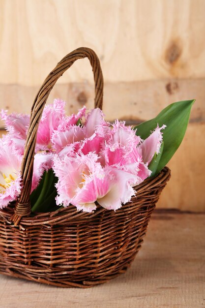 Schöne Tulpen im Weidenkorb, auf Holzuntergrund