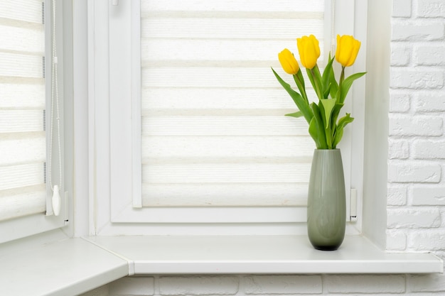 Schöne Tulpen in Vase auf weißem Fensterbrett